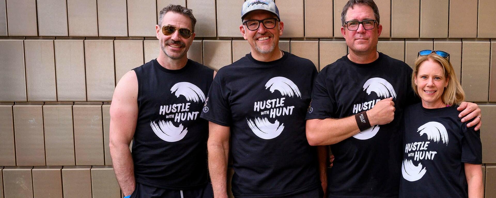 Dr. Matthew Hill, Rob Hunt, Trevor Johnston and Lindsey McKay stand together wearing Hustle with Hunt t-shirts.