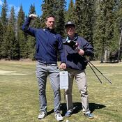 Two men on a golf course posing with golf clubs.