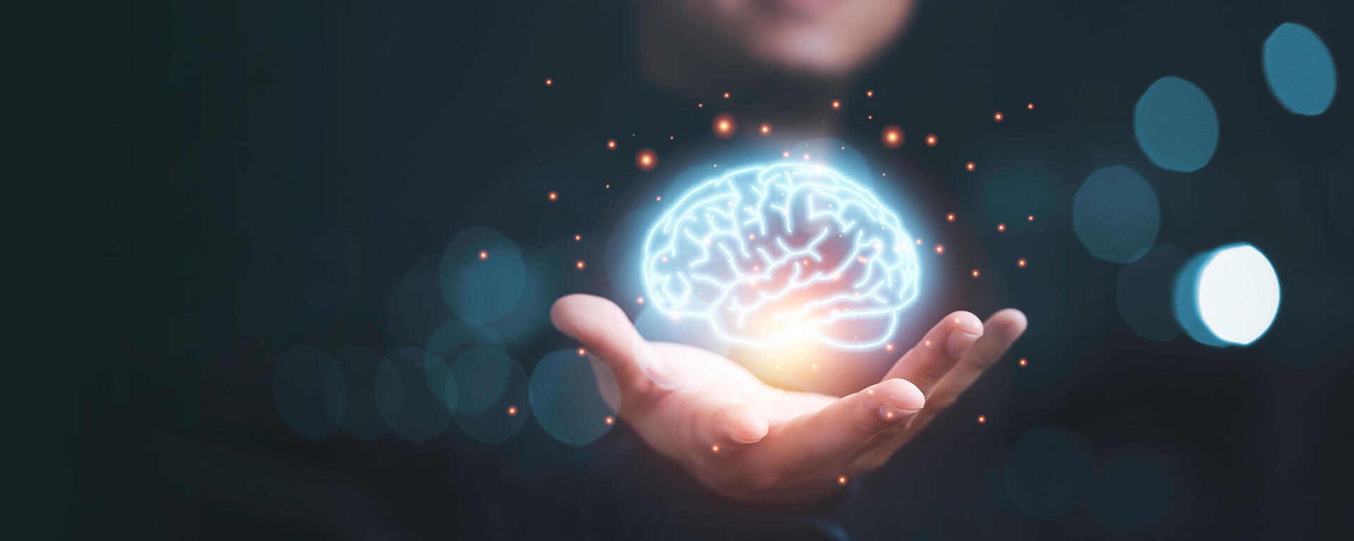 A man is reaching out his hand from the dark, with a blue and golden glowing brain hovering above, symbolizing the mission of MIST.