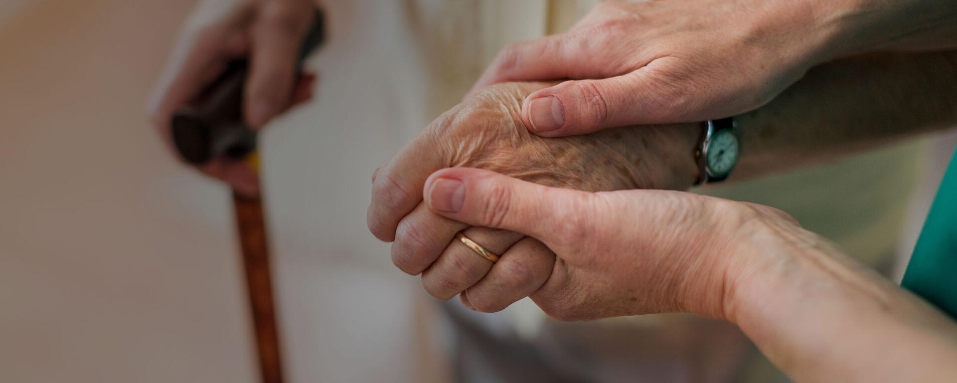 Two hands hold a senior woman's hand in a comforting and supportive way.