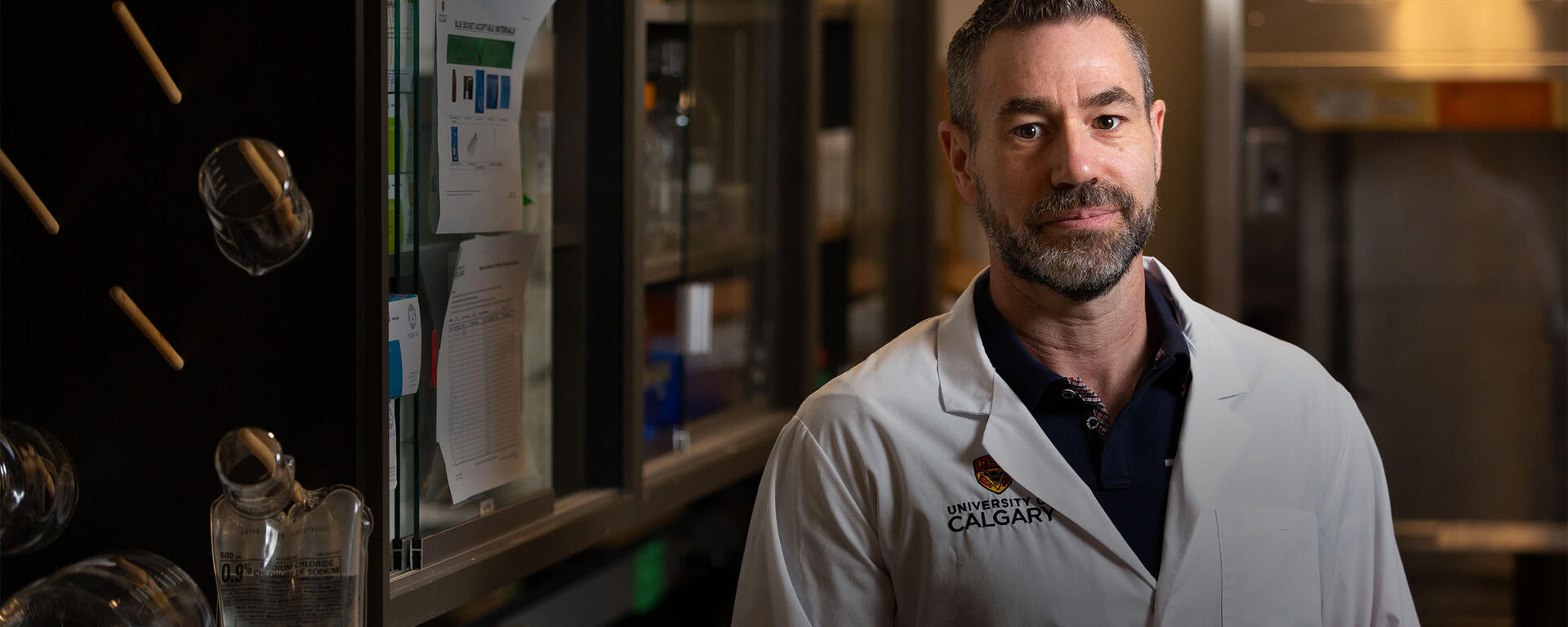 Dr. Matthew Hill stands in the foreground with his lab in the background.