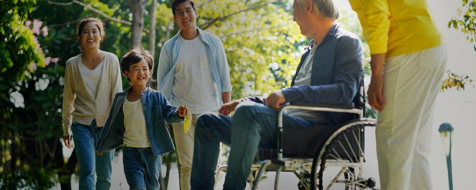 A senior man in a wheelchair smiles as his grandson runs up to him.