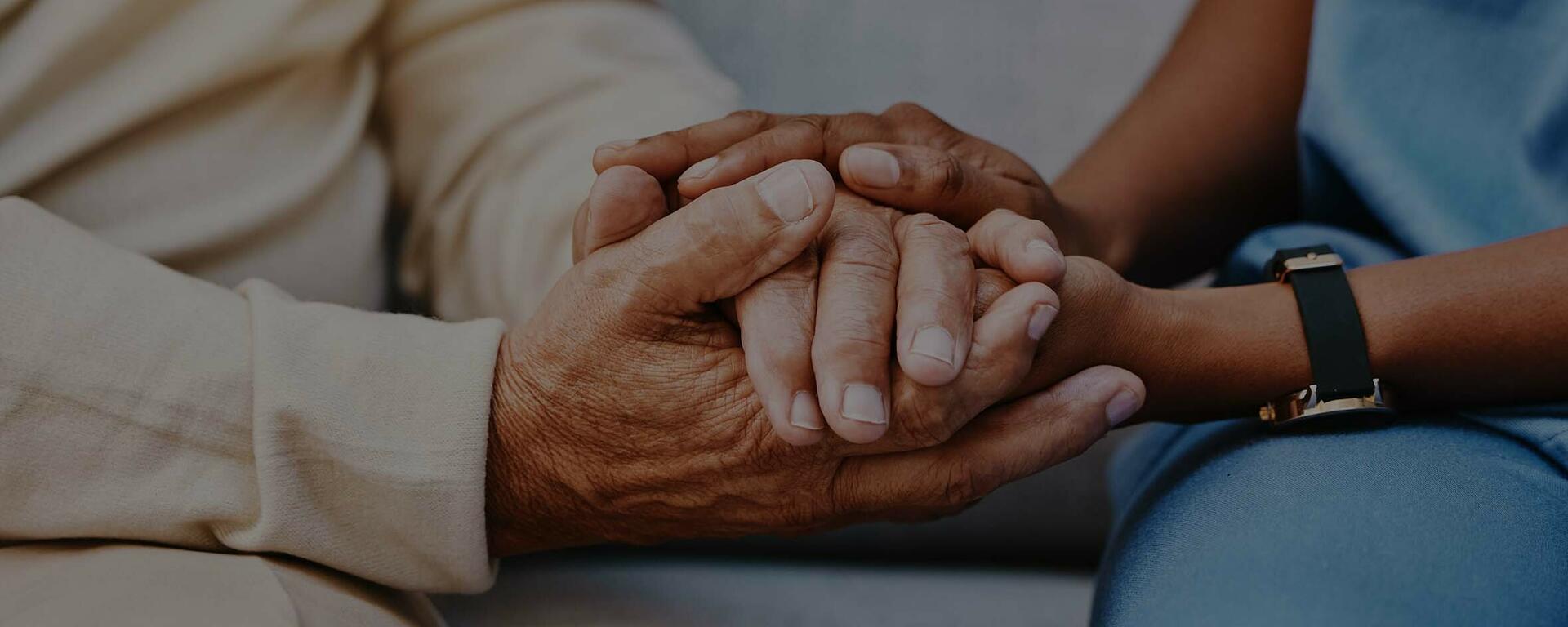A practitioner holds a patient's hands.