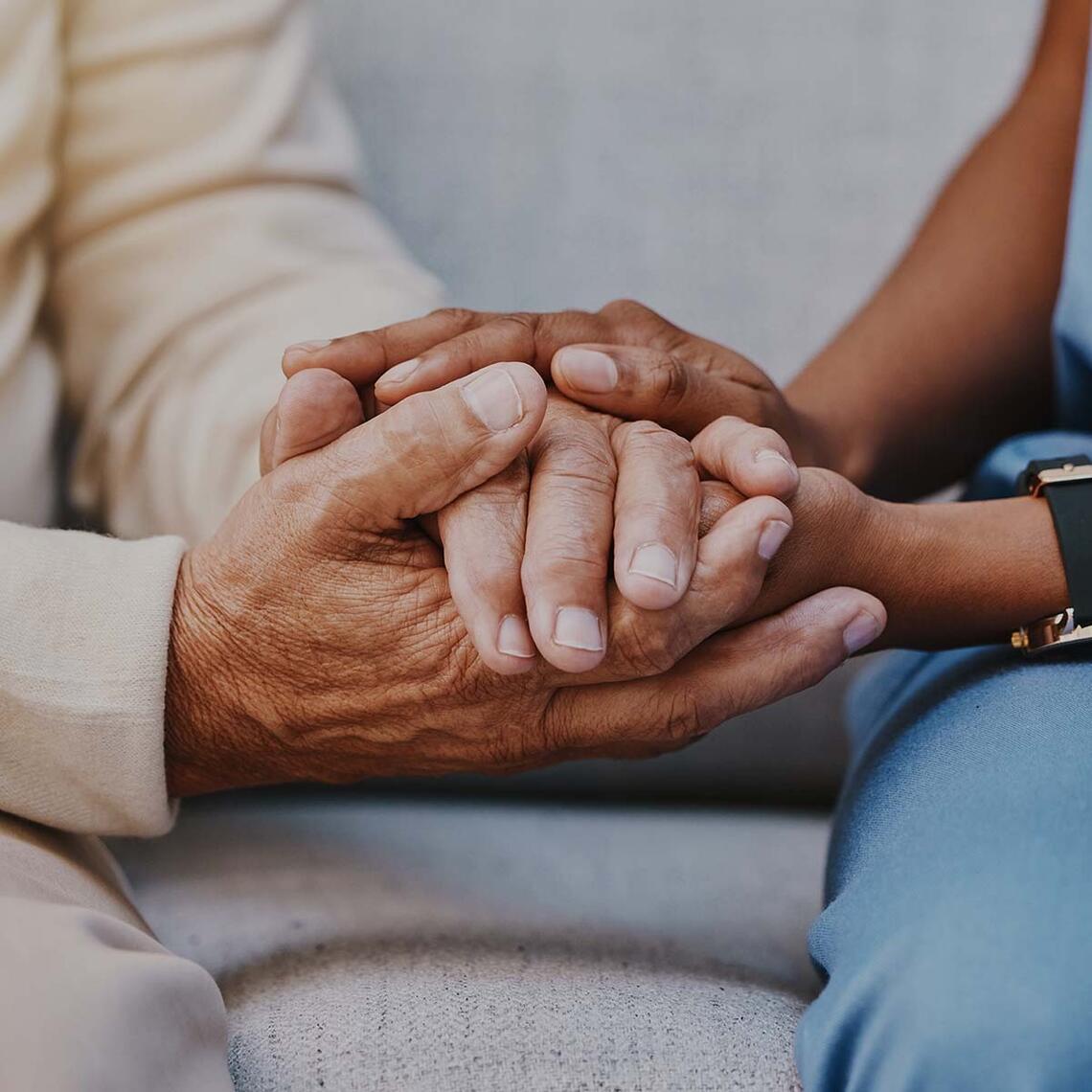 A practitioner holds a patient's hands.