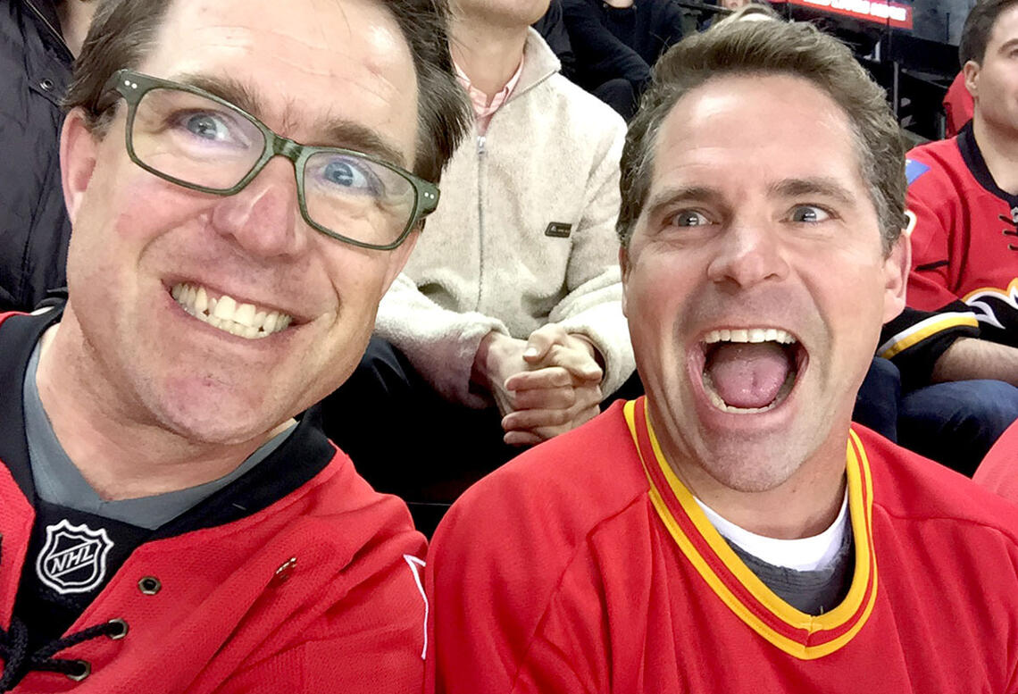 Mike McClay and Trevor Johnson taking a happy selfie while at a hockey game.
