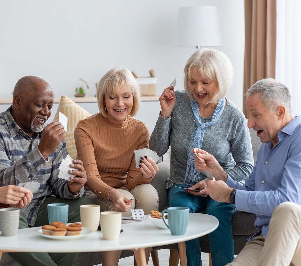 A group of four happy seniors play cards.