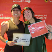 Two women holding signs saying “I'm spinning for mental health” and “I'm spinning for MIST.”