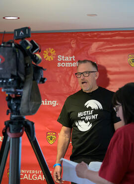 Rob Hunt speaking to media, in front of a University of Calgary backdrop.