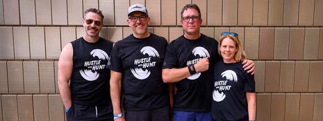 Dr. Matthew Hill, Rob Hunt, Trevor Johnston and Lindsey McKay stand together wearing Hustle with Hunt t-shirts.
