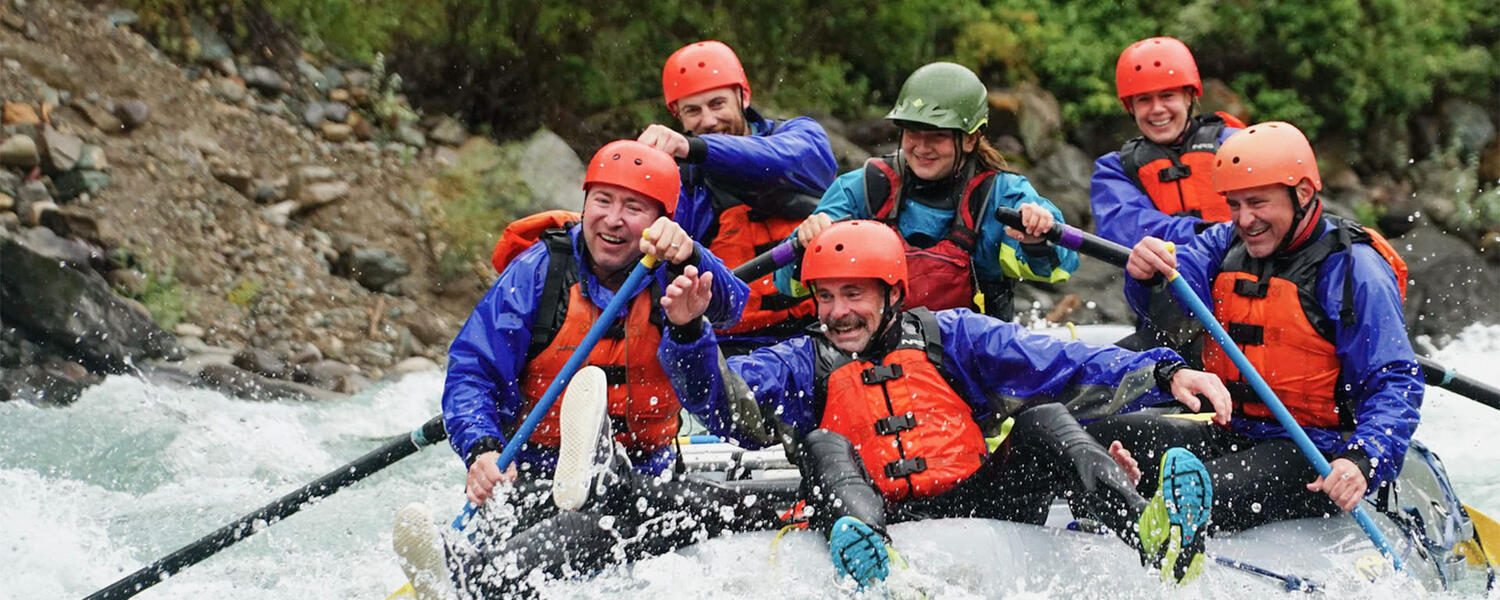 Mike McClay laughing while white water rafting with friends and wife, Lindsey McKay.